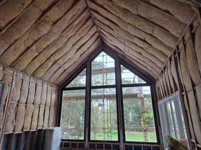 Pink insulation batts laid between ceiling joists in a roof space