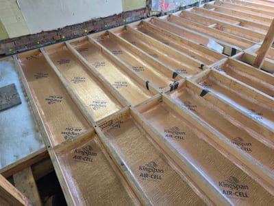Installer fitting underfloor insulation between joists in a subfloor crawl space