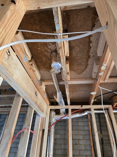 Black foam lagging wrapped around hot water pipes in a roof space